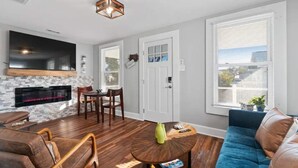 Een woonkamer met een open haard, een bank, een salontafel en een aan de muur bevestigde televisie.