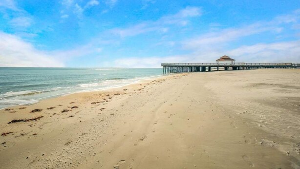Een strand met een pier die zich uitstrekt in de oceaan.