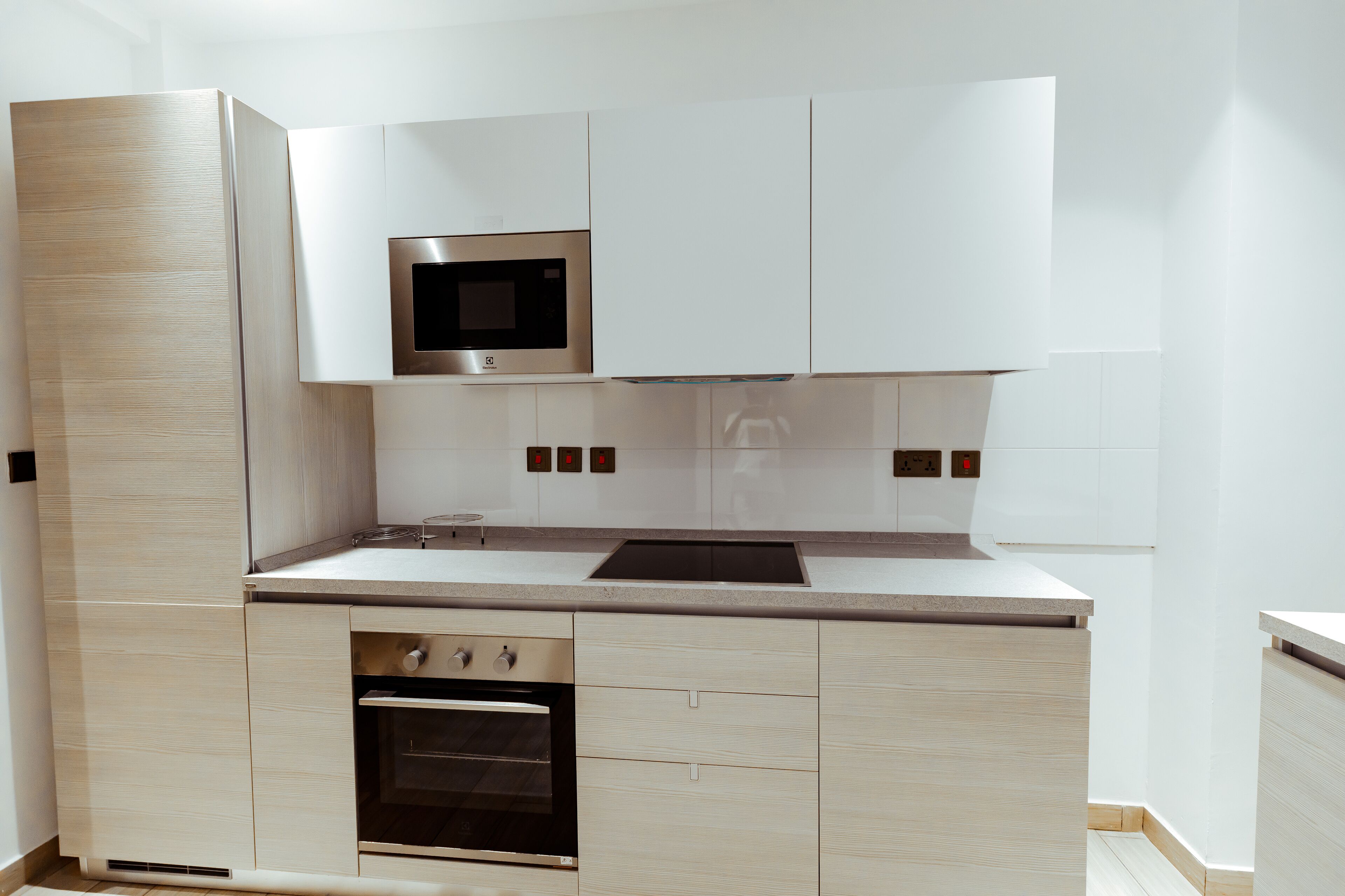 Una cocina moderna con armarios blancos, un microondas empotrado y un horno de acero inoxidable.