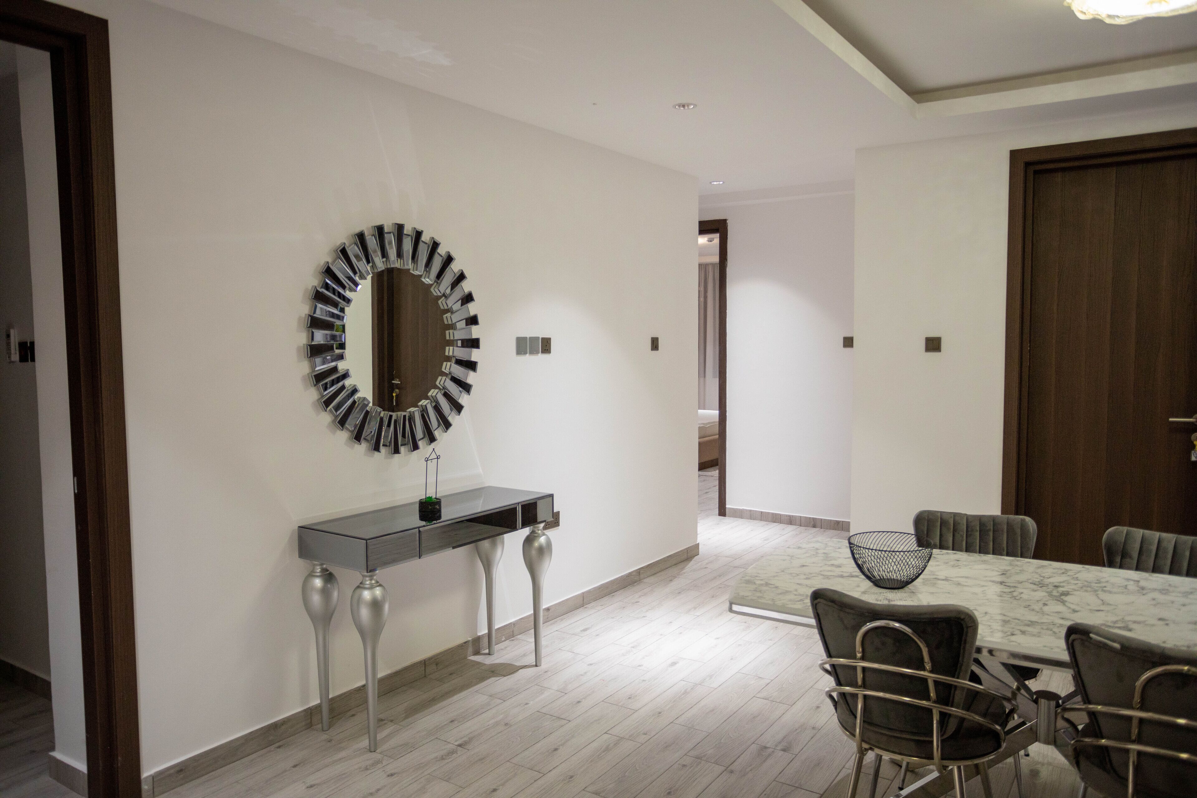 A modern dining area with a marble table, metal chairs, and a decorative mirror on the wall.