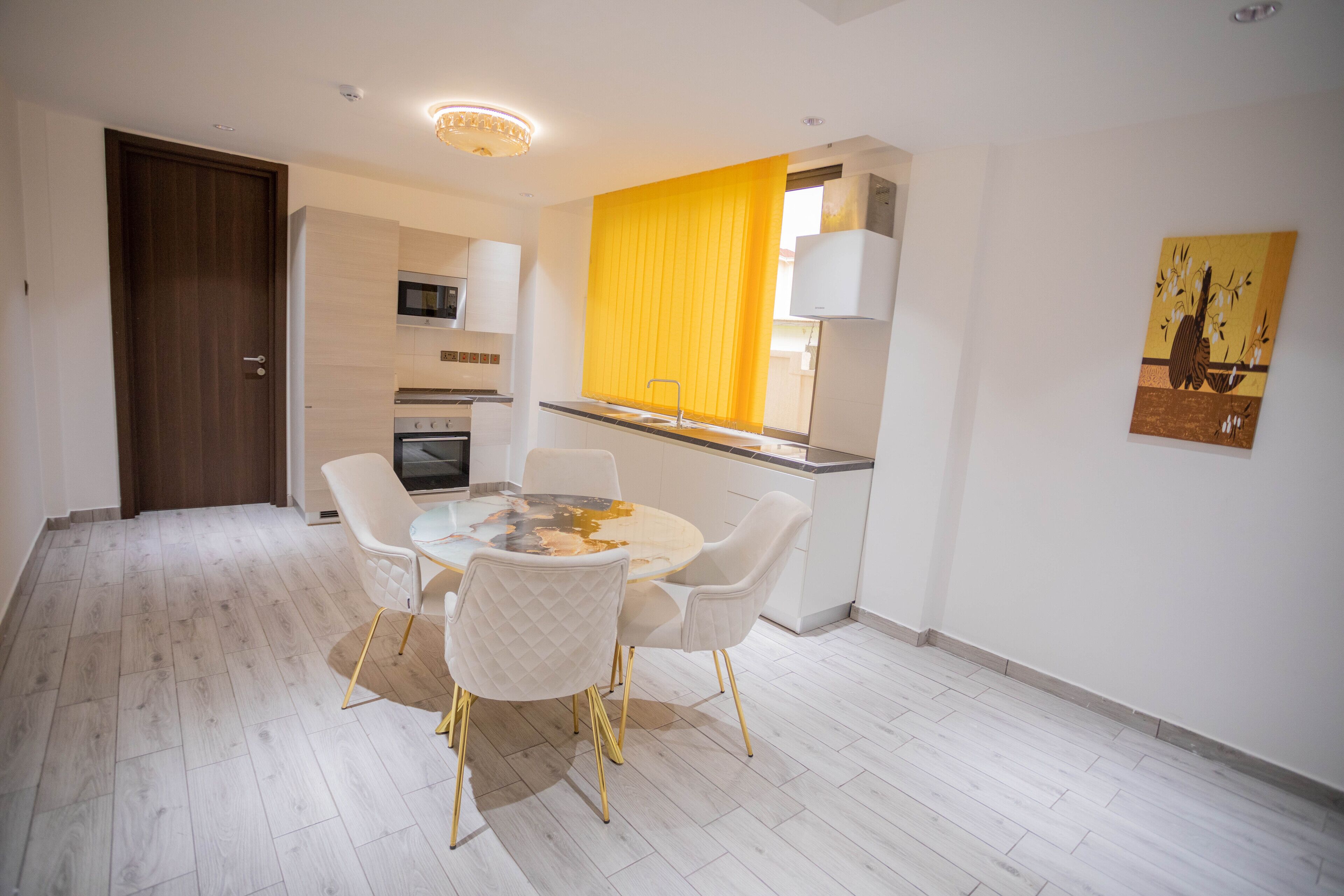 A modern kitchen with a microwave, oven, and a yellow curtain.