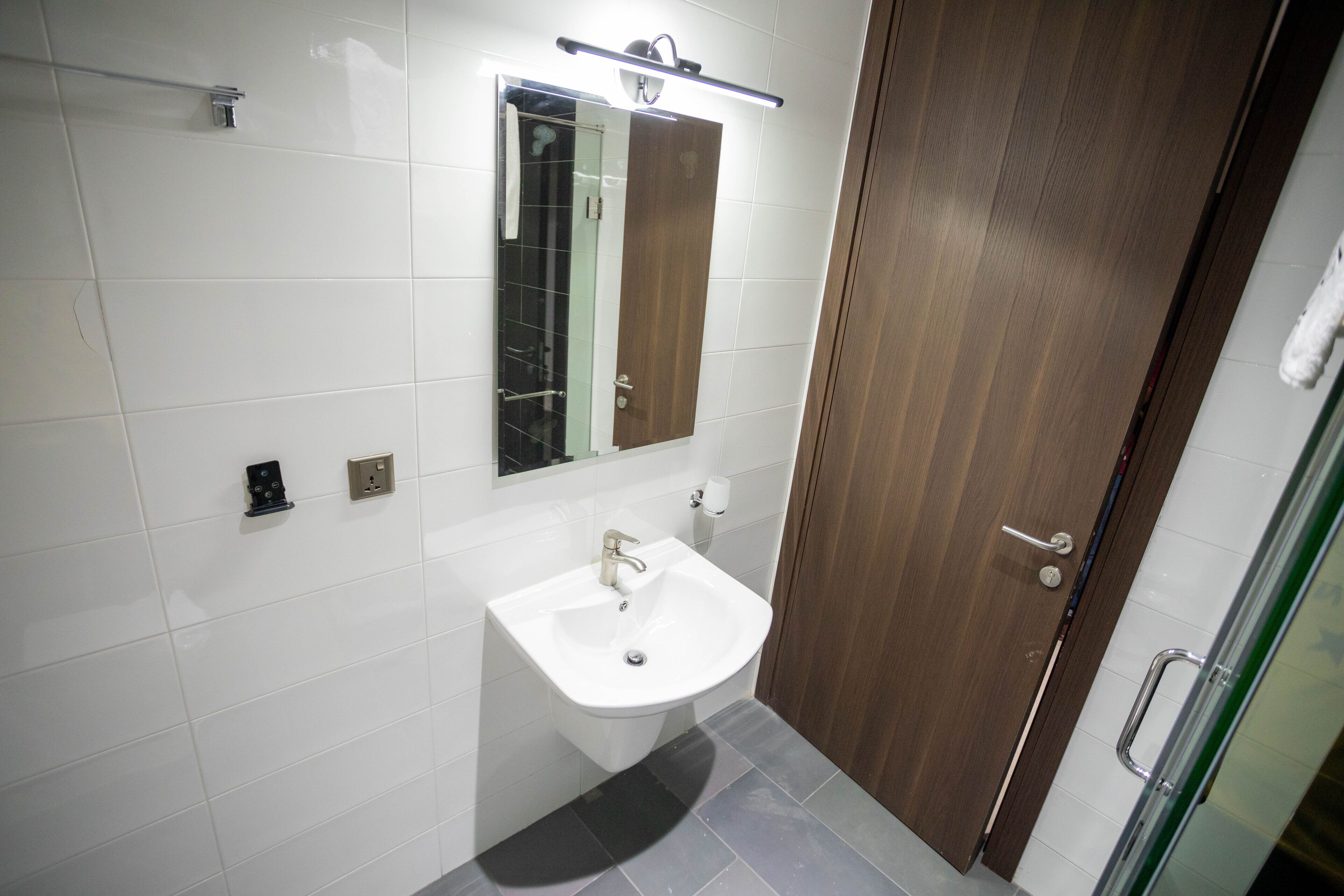 A bathroom with a white sink, a mirror, and a wooden door.