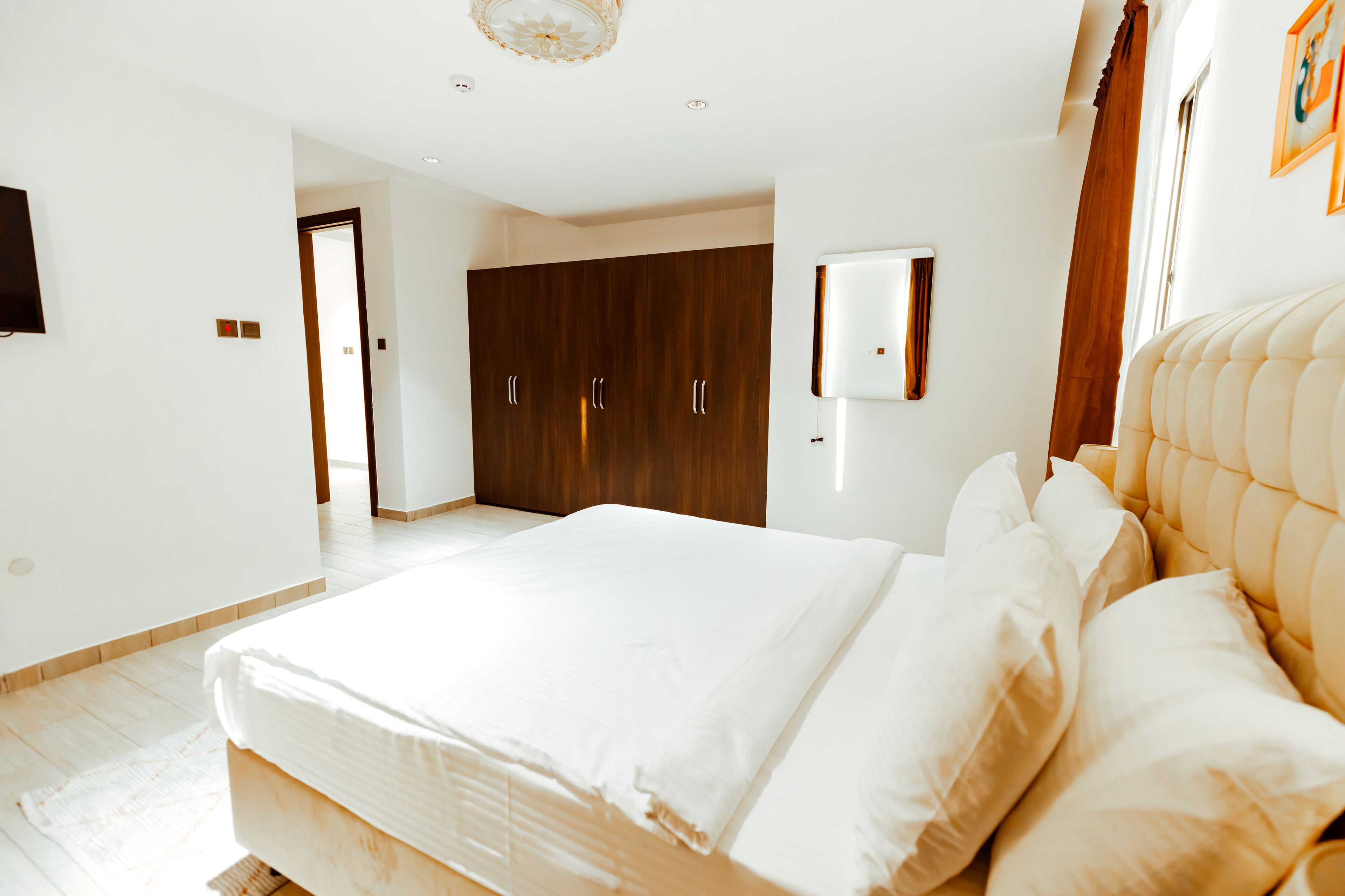 A bedroom with a large bed, a wardrobe, and a wall-mounted TV.
