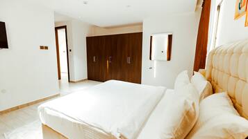 Un dormitorio con una cama grande, un armario y un televisor montado en la pared.