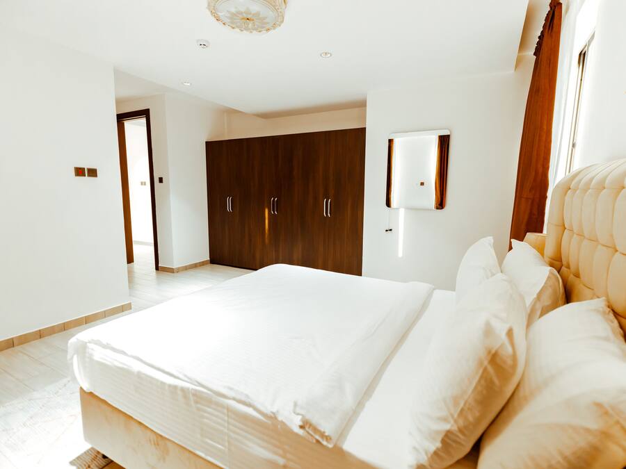 Un dormitorio con una cama grande, un armario y un televisor montado en la pared.