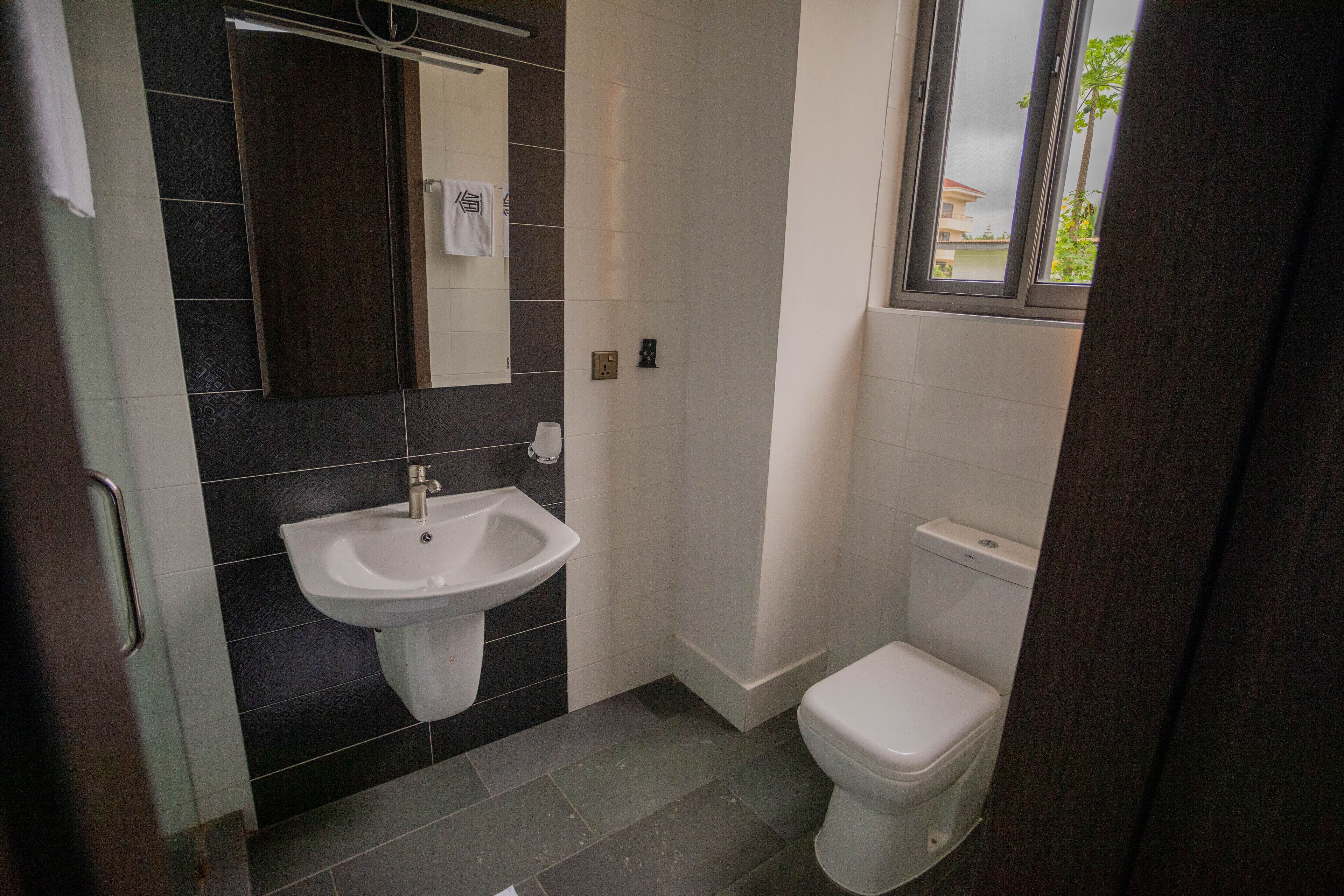 A bathroom with a sink, toilet, and a mirror.