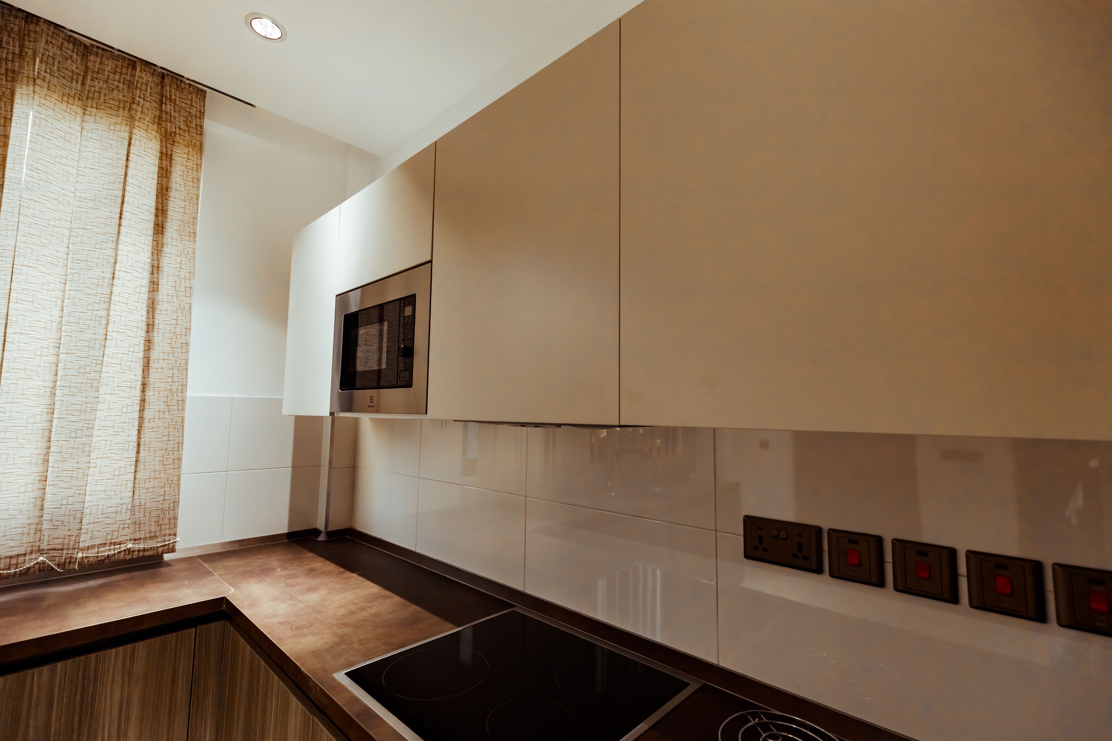 A modern kitchen with a built-in stove, white cabinets, and a microwave.