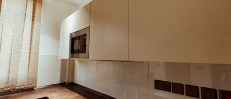 A modern kitchen with a built-in stove, white cabinets, and a microwave.