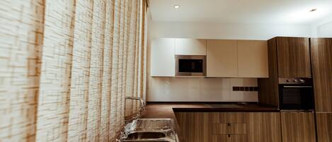 Una cocina moderna con un lavamanos de acero inoxidable, armarios de madera y un microondas.