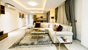 Een moderne woonkamer met een witte bank, salontafel en een vloerkleed met dessin.