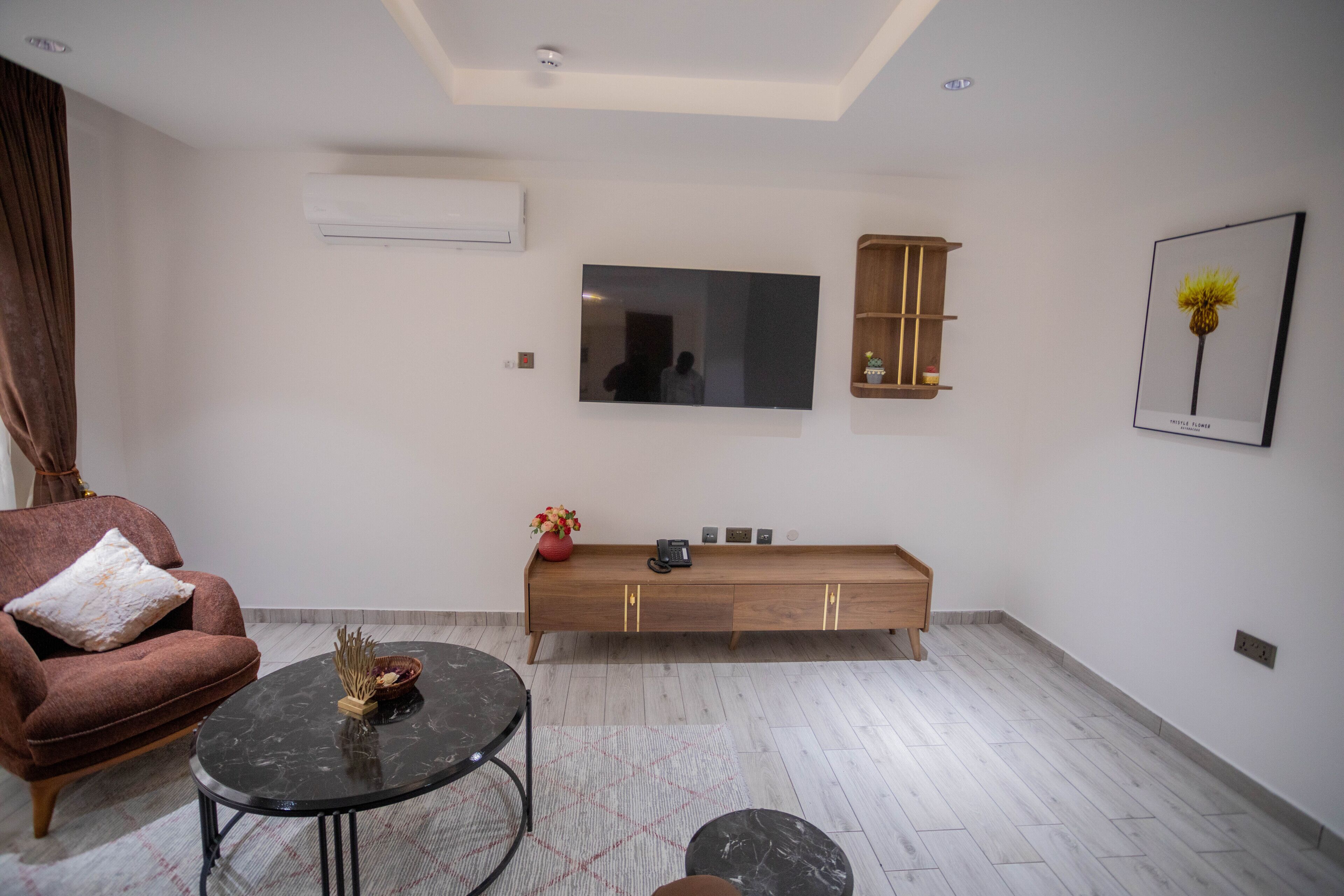 Una sala de estar moderna con sofá, mesa de centro, televisor, consola de madera y un cuadro enmarcado en la pared.