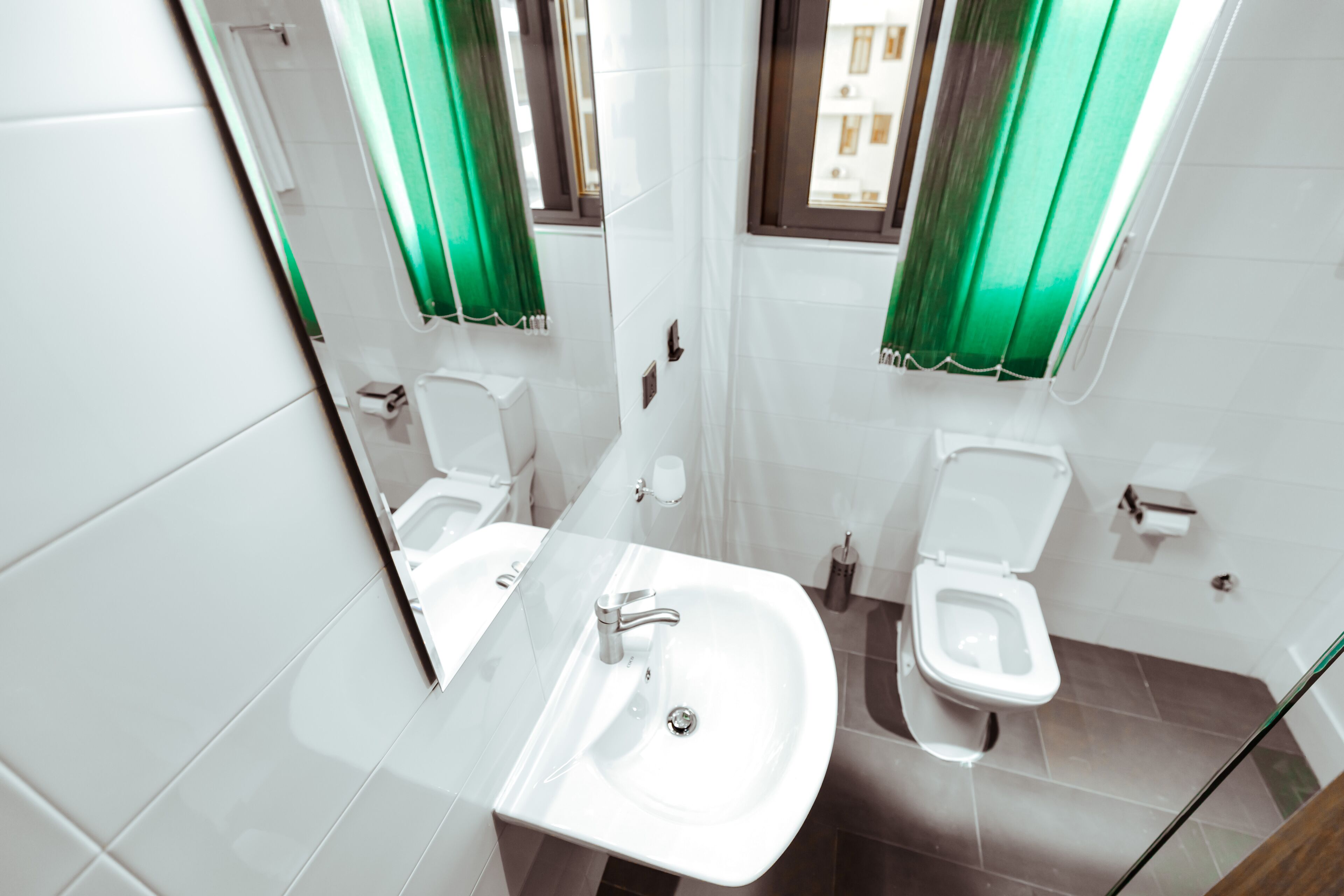 Un baño moderno con lavamanos de vidrio, un inodoro y una zona de ducha.
