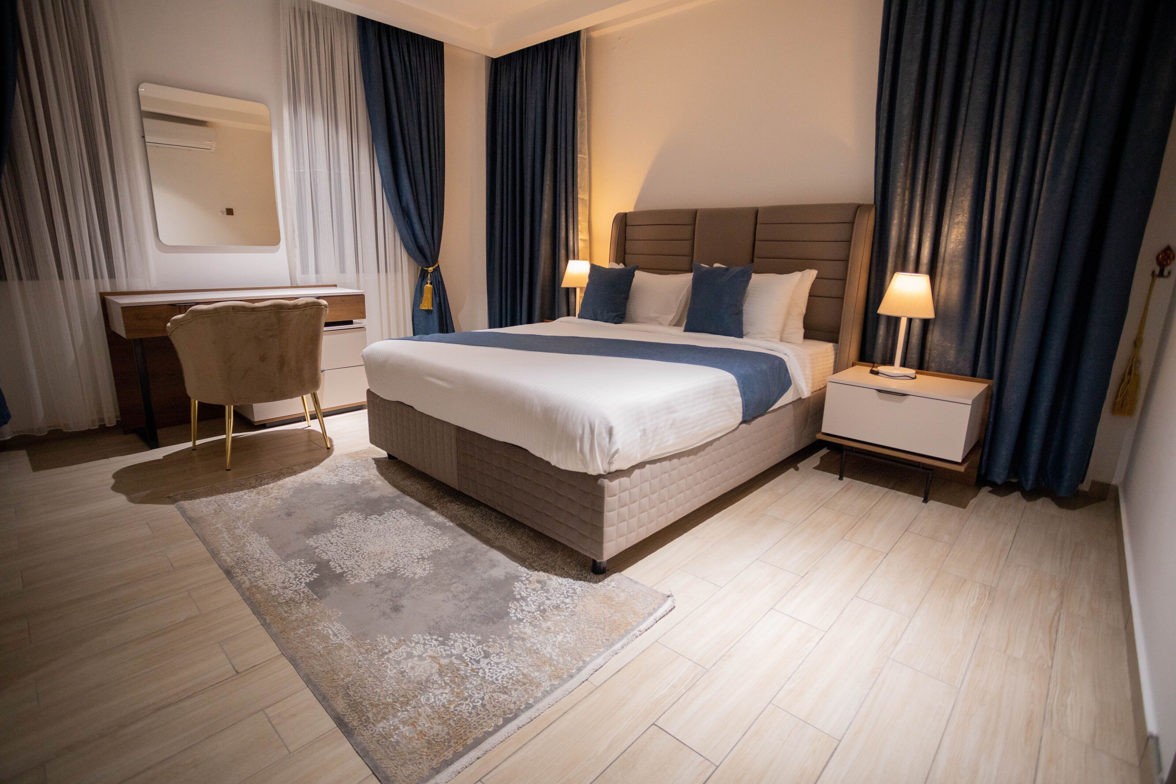 Habitación de hotel con una cama grande, mesitas de noche con lámparas, un escritorio y una silla.