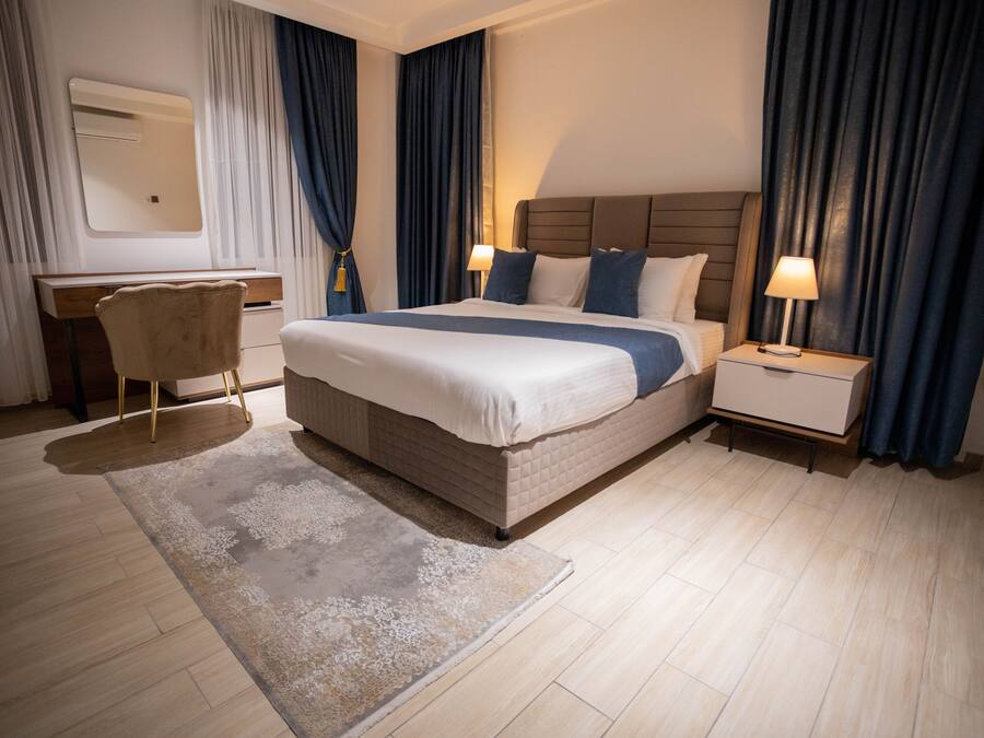 Habitación de hotel con una cama grande, mesitas de noche con lámparas, un escritorio y una silla.