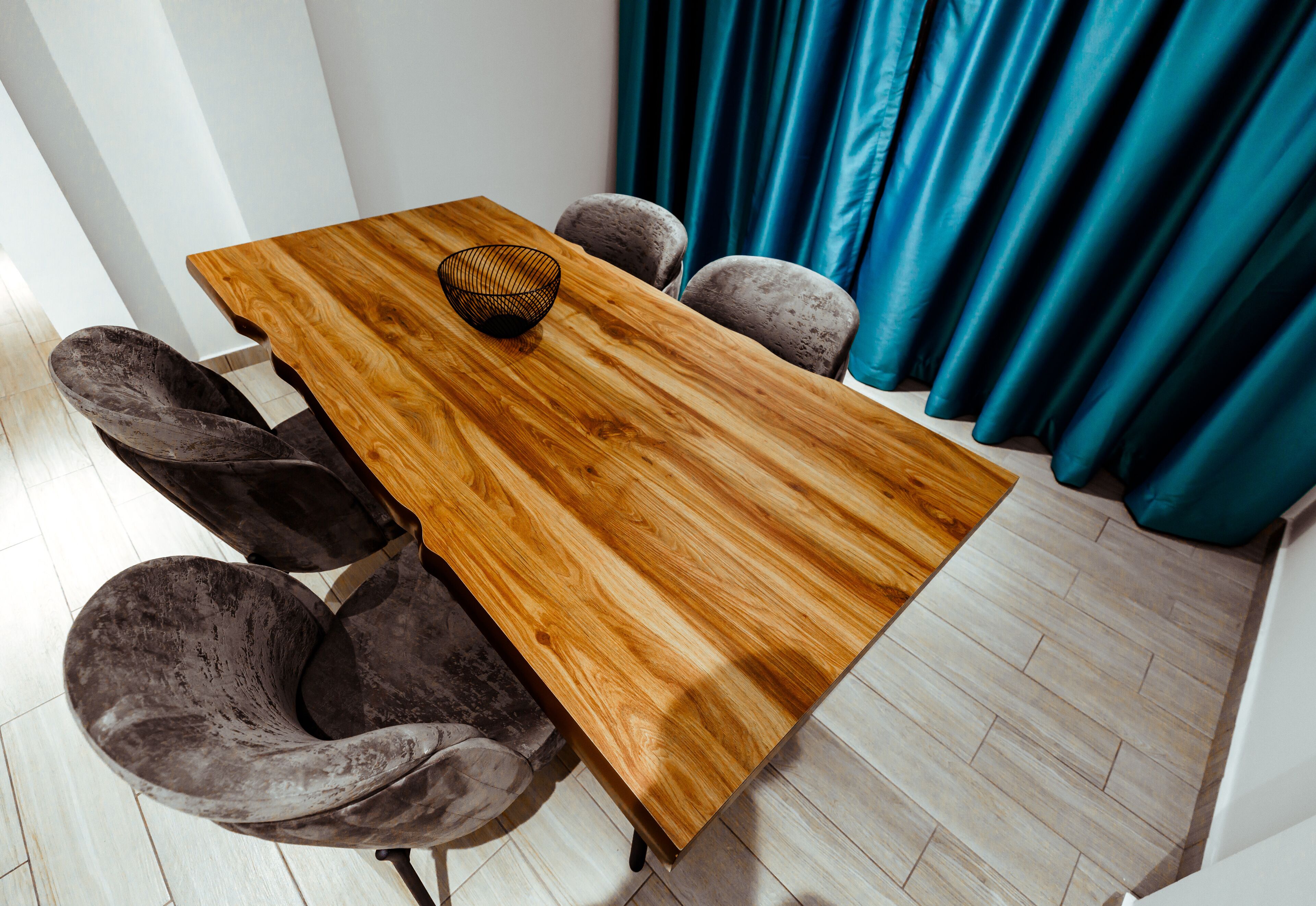 A wooden table with a woven bowl, surrounded by four cushioned chairs.