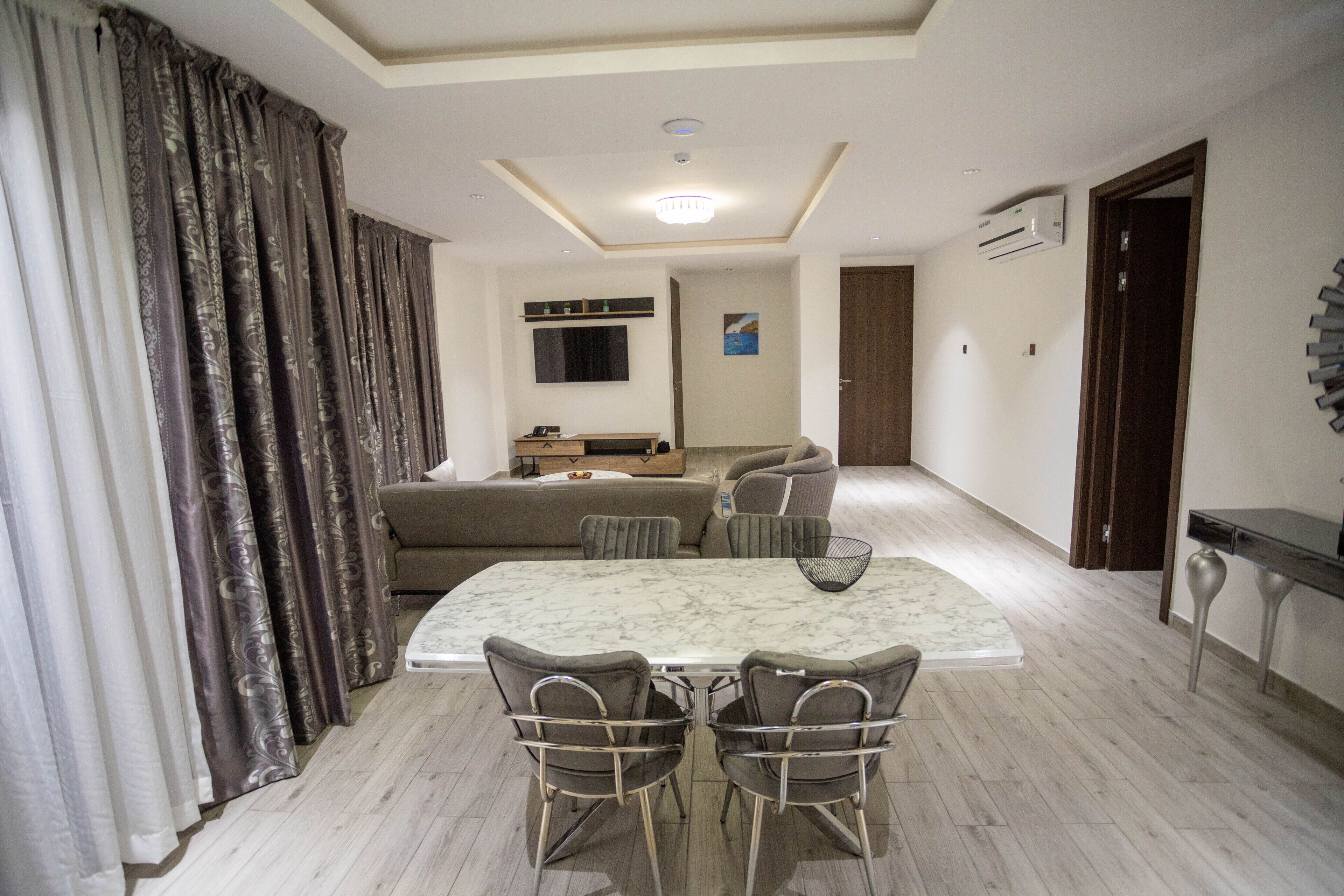 A modern living room with a dining area, a sofa, a TV, and a wooden floor.