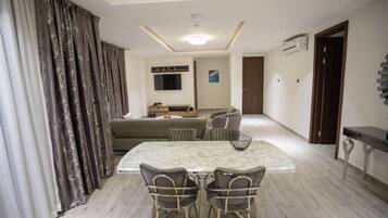 Una sala de estar moderna con comedor, sofá, televisor y piso de madera.