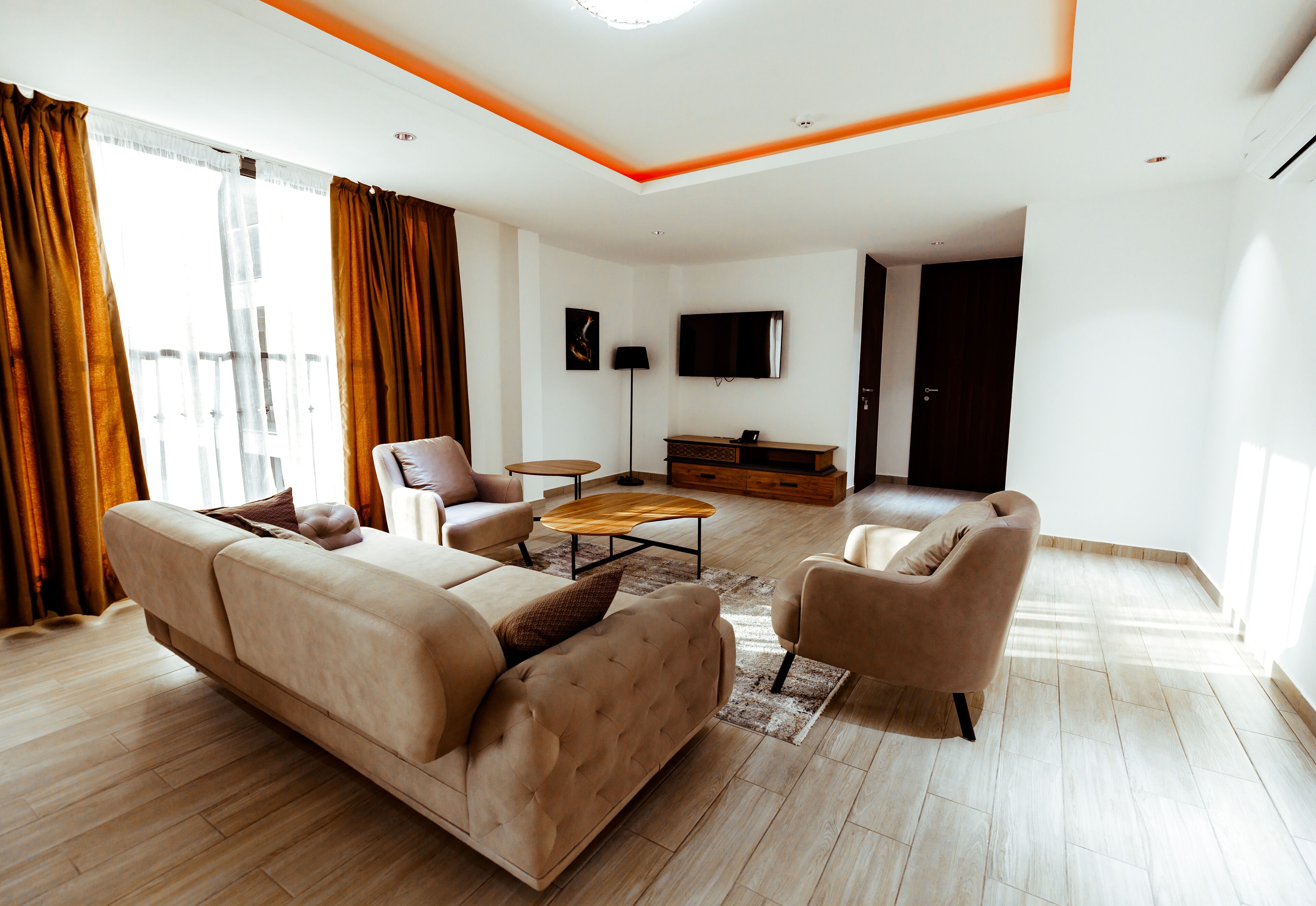A modern living room with a sofa, armchairs, a coffee table, and a TV.