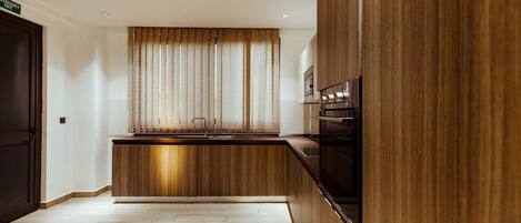 Una cocina moderna con armarios de madera, horno empotrado y ventana con cortinas.