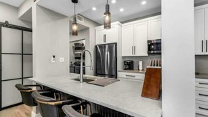 A modern kitchen with white cabinets, stainless steel appliances, and pendant lighting. - Wonderful Avalon Condo (Ground Floor) - Renovated & Steps to Pool!!!🏝️ (Clearwater)