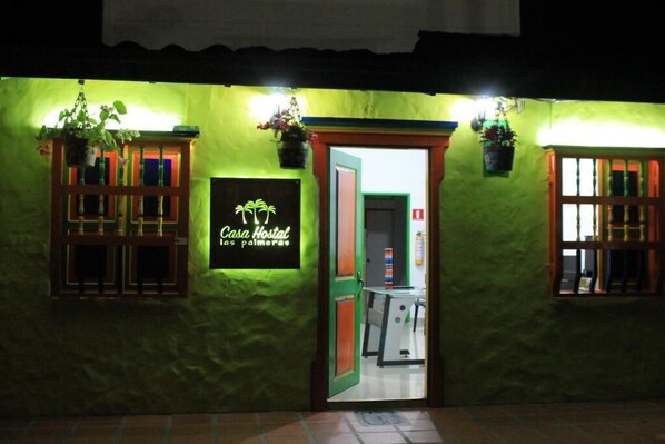 A green building with a sign reading "Casa Hostal las palmeras."