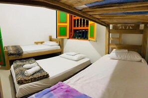 A dormitory room with bunk beds, a window with colorful shutters, and a bed with a leopard print blanket.