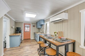 Eine Küche mit einer Holztheke, Barhocker und einem Esstisch, gedeckt mit Glaswaren und einer Vase.
