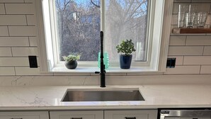 Une cuisine moderne équipée d’un lave-vaisselle en acier inoxydable, d’un évier double et de meubles de rangement intégrés.