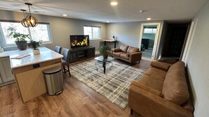 Un salon moderne avec un plancher en bois, un canapé, une table basse et un téléviseur.