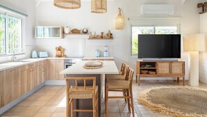 Une cuisine moderne avec des meubles en bois, un îlot central et un coin repas doté de chaises en osier.
