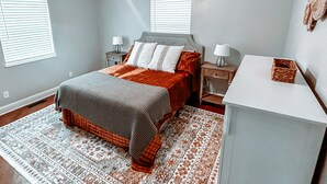 A bedroom with a bed, nightstands, a desk, and a ceiling fan.