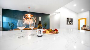 A modern kitchen with a marble countertop, two wine glasses, a bottle of wine, and a charcuterie board. - The Blue Cactus in Palm Springs: Family-Friendly, Pool/Spa, Game Room & Fire-Pit (Palm Springs)