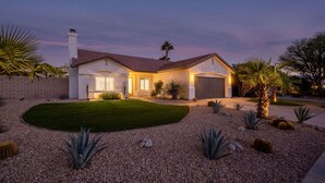 A single-story house with a well-maintained lawn, a gravel driveway, and various desert plants. - The Blue Cactus in Palm Springs: Family-Friendly, Pool/Spa, Game Room & Fire-Pit (Palm Springs)