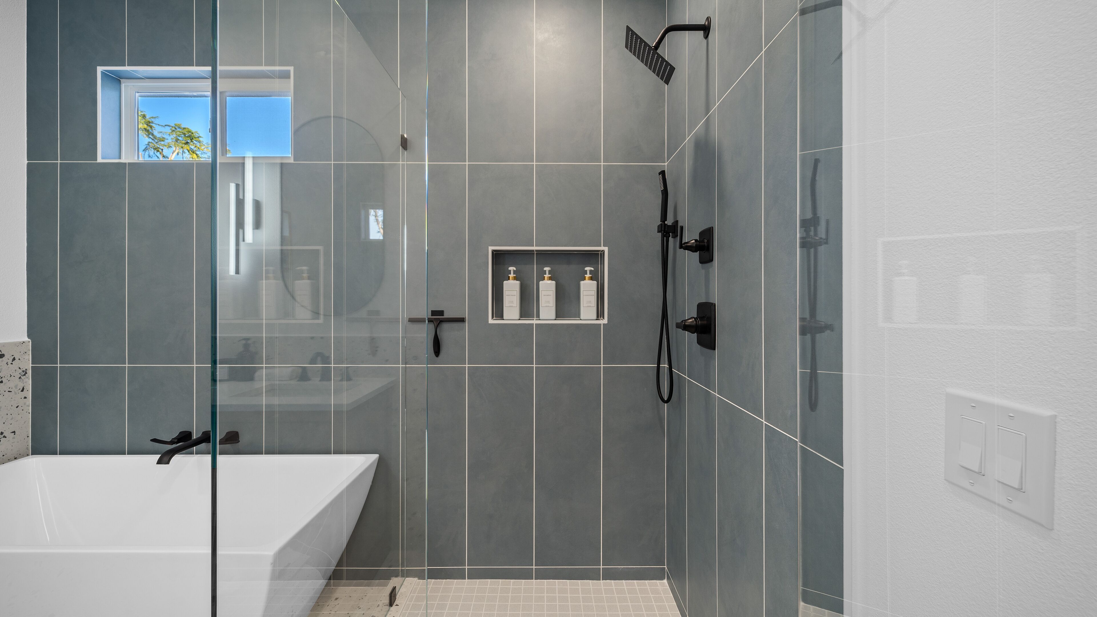 A modern bathroom with a bathtub, a glass-enclosed shower area, and a vanity with a mirror.