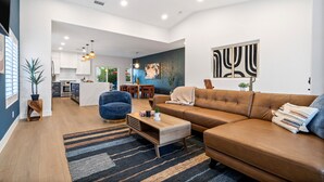 A modern living room with a brown leather sofa, a blue armchair, and a wooden coffee table. - The Blue Cactus in Palm Springs: Family-Friendly, Pool/Spa, Game Room & Fire-Pit (Palm Springs)