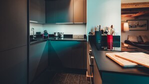 Eine moderne Küche mit dunkler Arbeitsplatte, Holzbalken an der Decke und einer türkisblauen Spritzschutzwand.