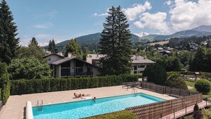 Ein Schwimmbecken mit Blick auf ein Gebirge, umgeben von Häusern und Bäumen.