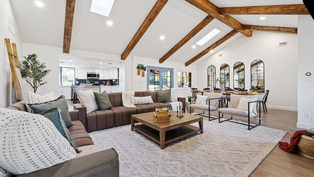 A spacious living room with a high ceiling and exposed wooden beams, a cozy seating area with sofas and a coffee table, and a dining area with chairs and tables. - Free Heated Pool ~ Hot Tub ~ Basement Game Room ~ Large Backyard (Mesa)
