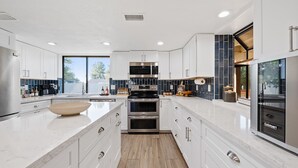 A modern kitchen with white cabinetry, a large island, stainless steel appliances, and a view to the outside. - Free Heated Pool ~ Hot Tub ~ Basement Game Room ~ Large Backyard (Mesa)
