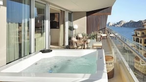 Un balcón con bañera de hidromasaje, zona de estar y vista al mar.