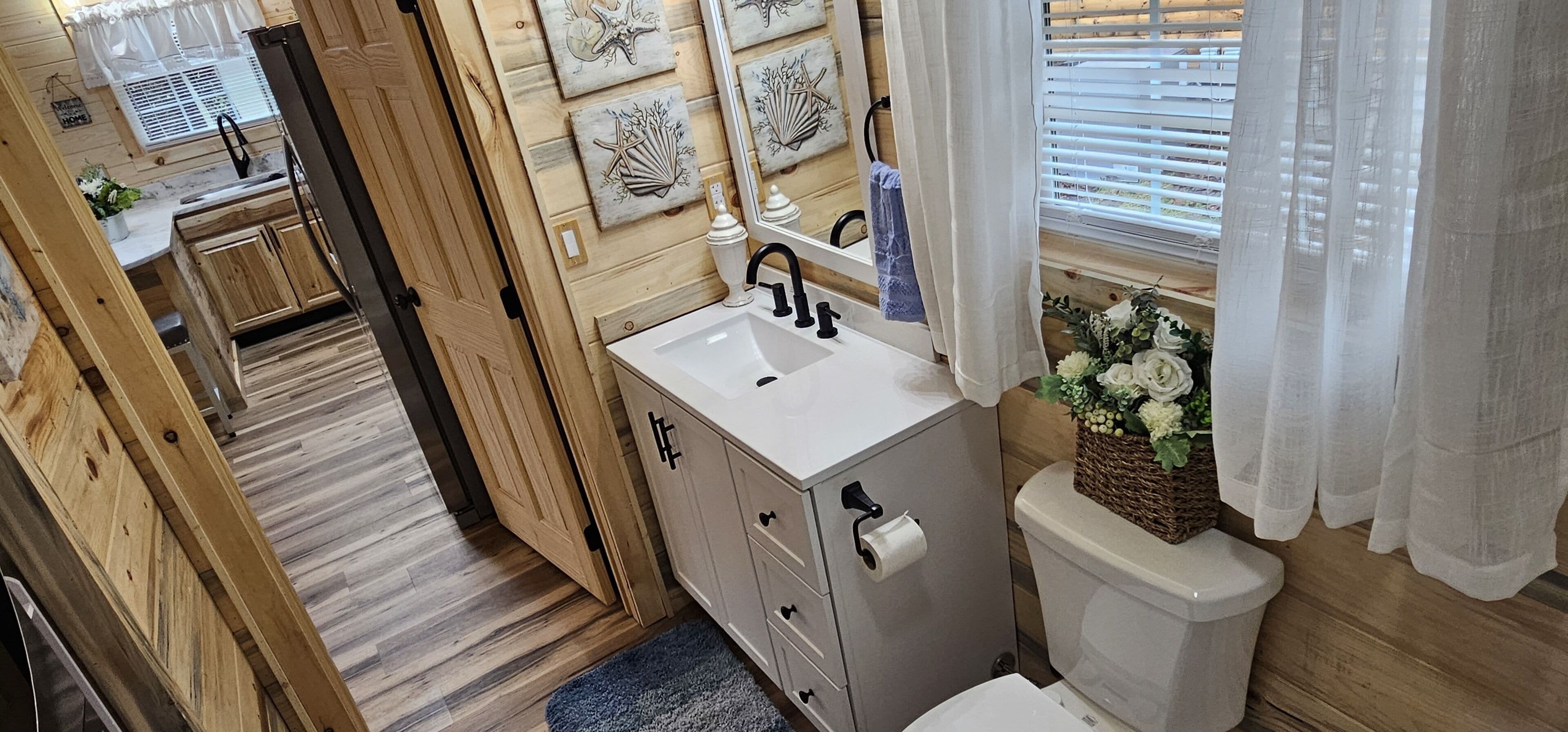 A wooden interior with a white sink, cabinet, and toilet.