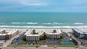 Ein Strandhotel mit mehreren Gebäuden, einem Parkplatz und einem Tennisplatz.