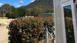 A building with a view of a hill and trees. - Oliver’s Hut - Hartley Huts (Hartley Vale)