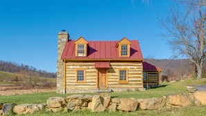 A log cabin with a red roof, stone chimney, and a stone foundation. - Historical Paris Cabin on Farm w/ Fire Pit! (Paris)