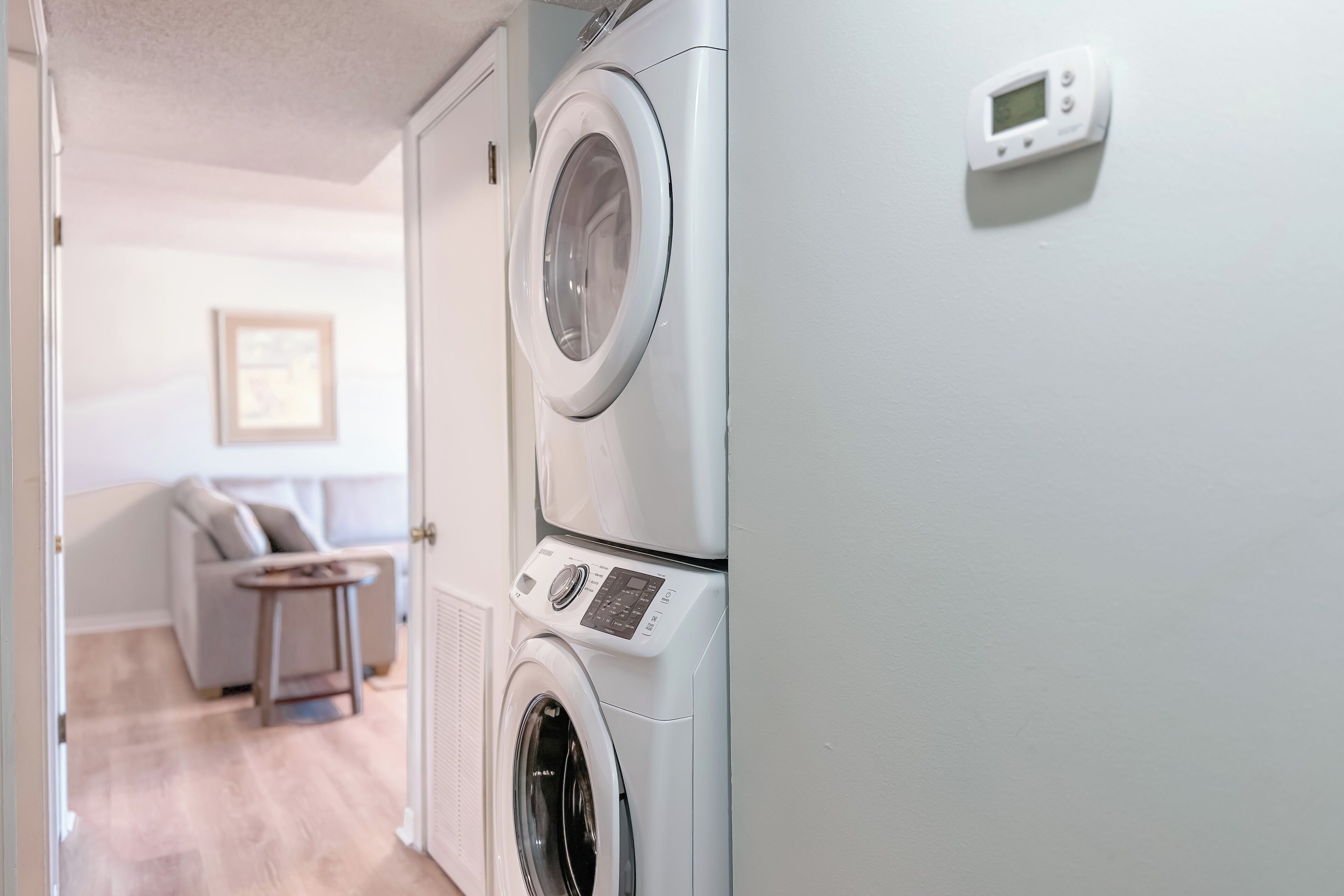A laundry room with stacked washing machines and a control panel.