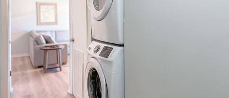A laundry room with stacked washing machines and a control panel.