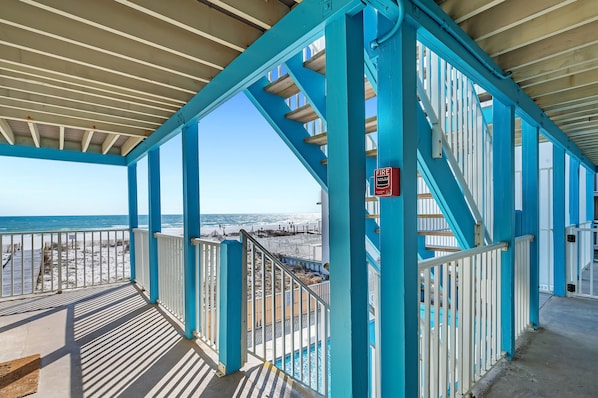 A covered outdoor area with a view of the beach and ocean.