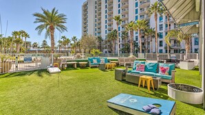 A rooftop pool area with artificial grass, outdoor furniture, and palm trees. - Palms of Destin Resort Condo: Beaches, Golf & More (Destin)