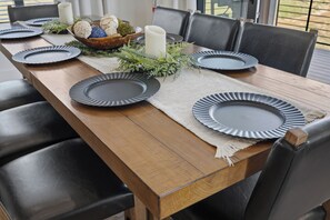 A wooden dining table set with plates, a bowl of decorative items, and a candle.