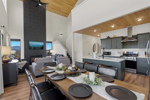 A modern kitchen with a central island, built-in appliances, and a dining area with a fireplace. - Sleek 4BR Cabin with Hot Tub, Theater & Arcade | Golf & Waterpark Nearby! (Sevierville)